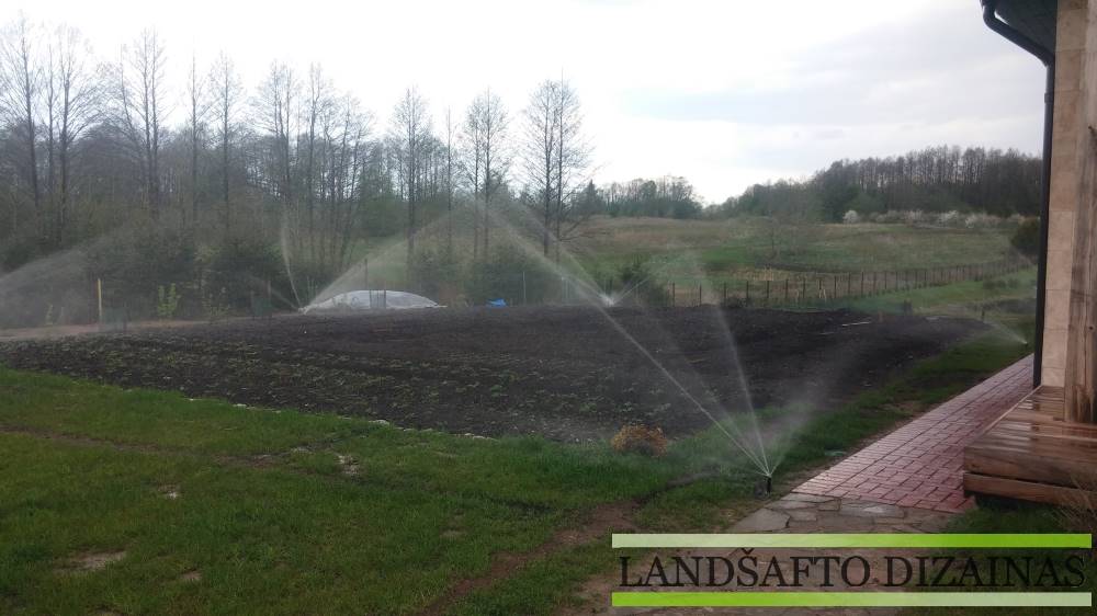 Veikiantys purkštuvai laisto paruoštos dirvos plotą šalia vejos
