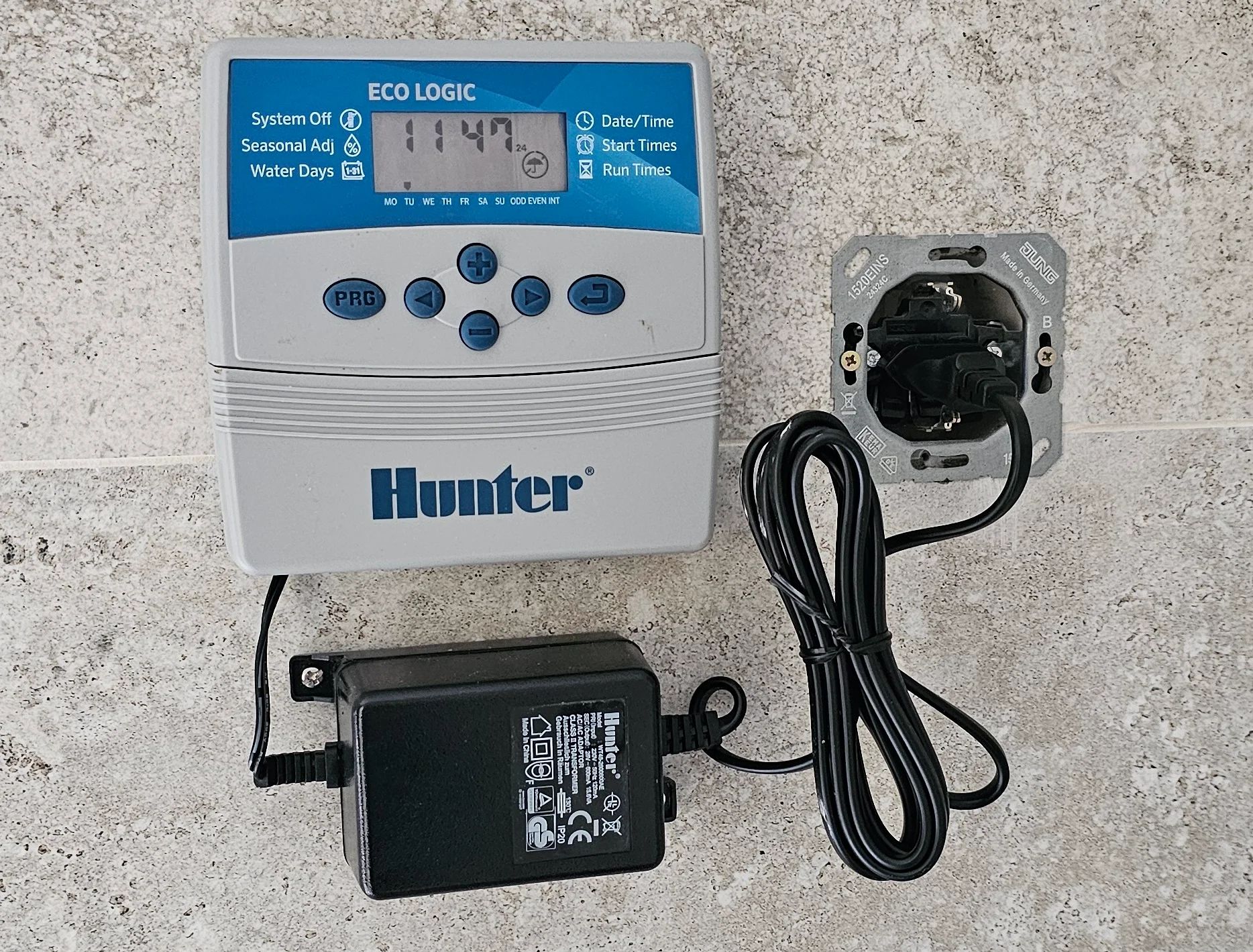 Hunter Eco Logic laistymo valdiklis su ekranu ir maitinimo adapteriu ant sienos