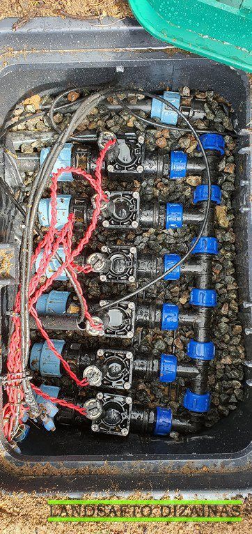 Elektromagnetinių laistymo vožtuvų grupė su laidais ir vamzdžiais vožtuvų dėžėje